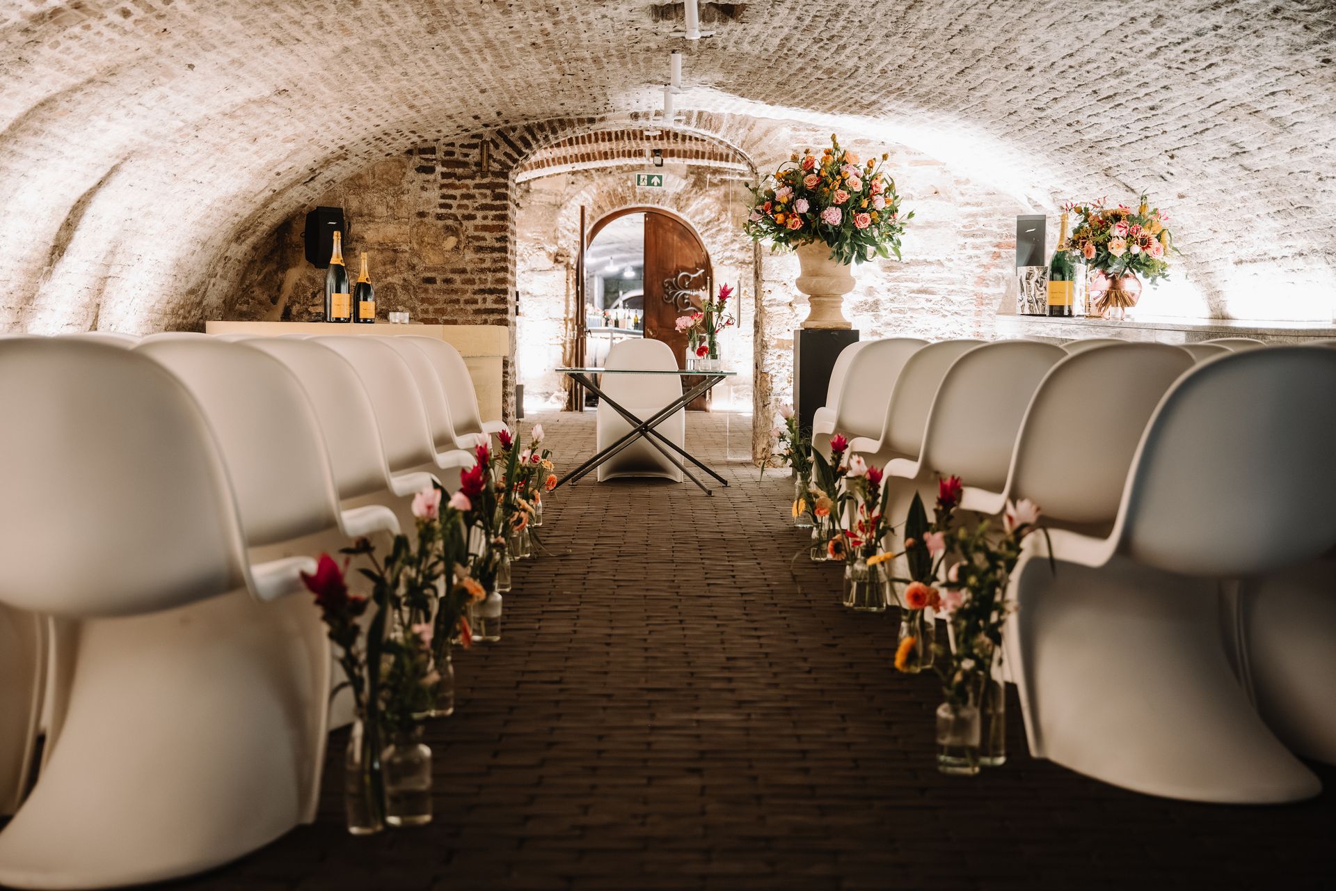 Romantische huwelijksceremonie opstelling met witte stoelen en bloemen in de historische wijnkelders van Thiessen Wijnkoopers.